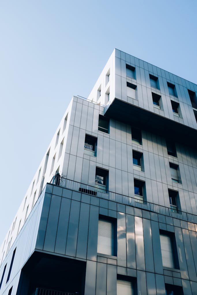 Low angle view of a modern skyscraper with glass windows set against a clear blue sky.