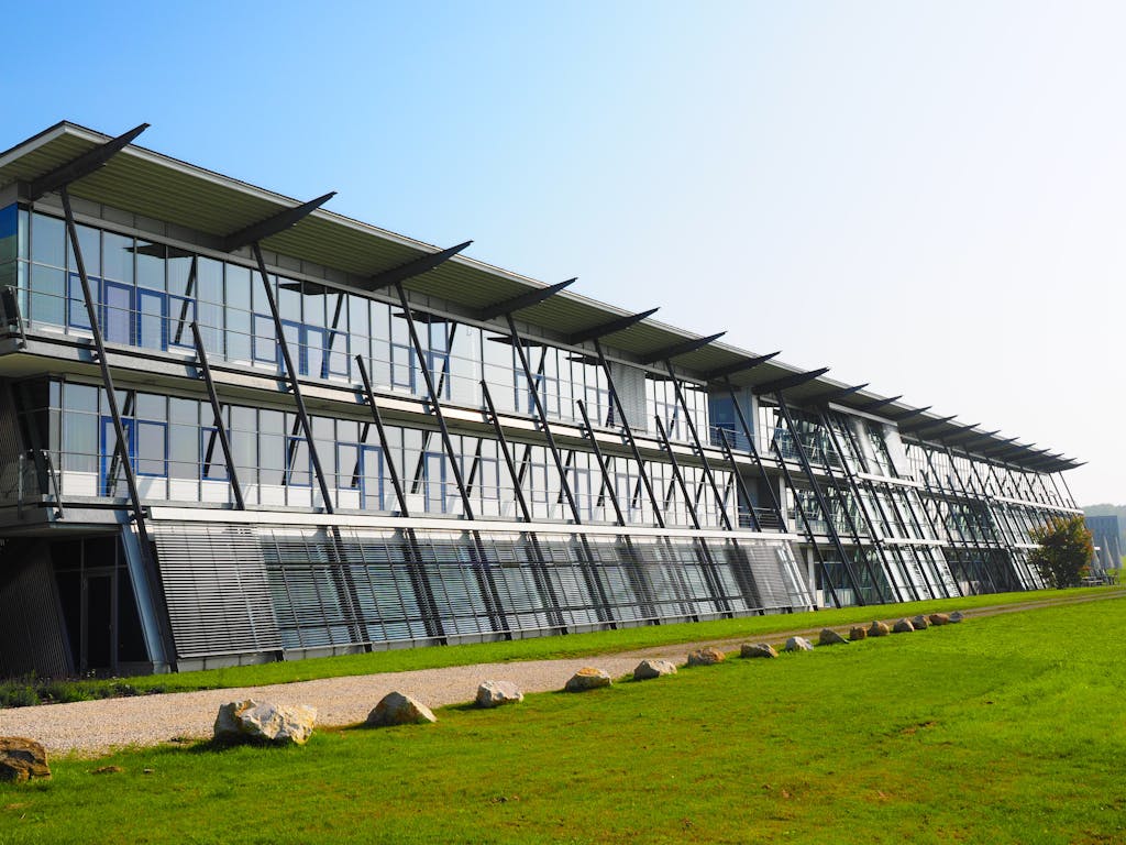 Sleek modern architecture with a glass facade and green lawn surroundings.