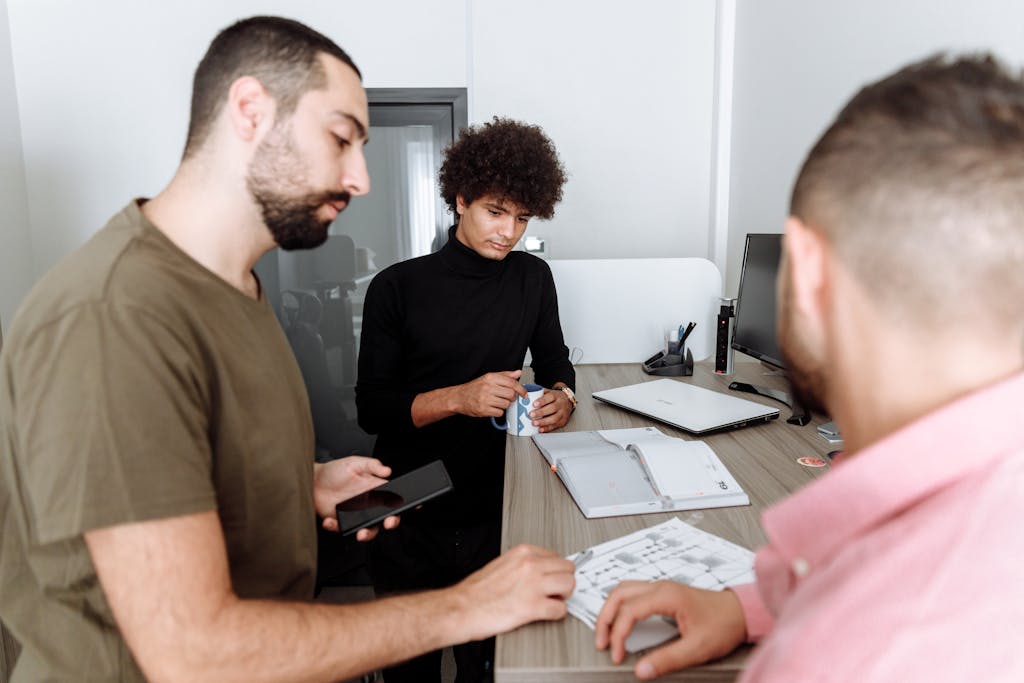 Three colleagues discussing work around a table in a modern office setting.